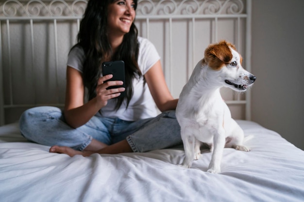 Seção média de mulher usando telefone inteligente sentada na cama em casa