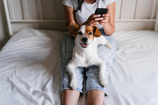 Seção média de mulher usando telefone inteligente sentada na cama em casa
