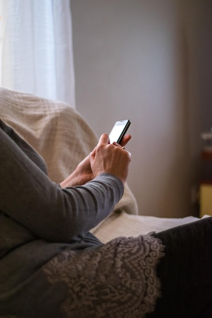 Seção média de mulher usando telefone móvel em casa