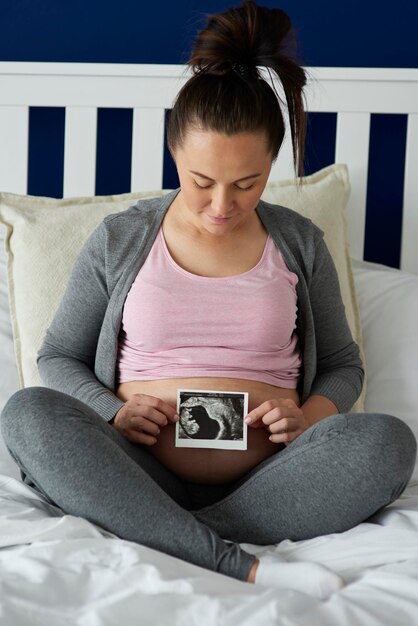 Foto seção média de mulher usando telefone móvel enquanto está sentada na cama