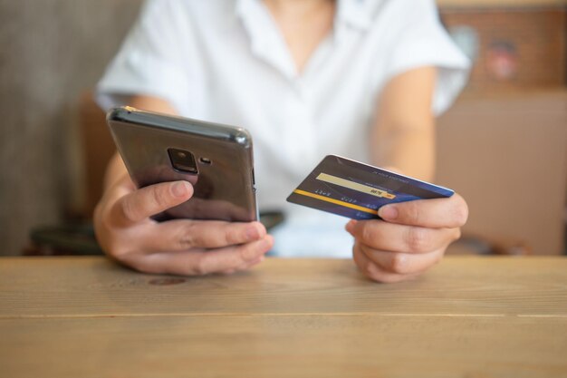 Seção média de mulher usando telefone móvel na mesa