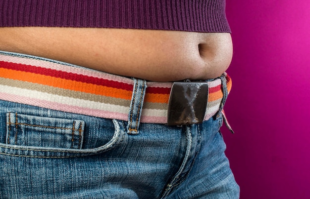 Foto seção média de mulher vestindo top de colheita de pé contra fundo rosa