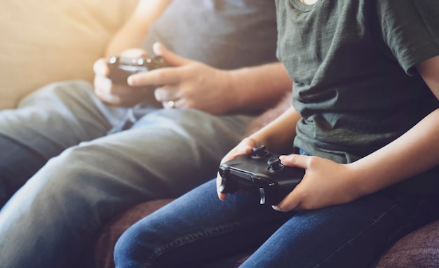 Seção média de pai e filho jogando videogame em casa