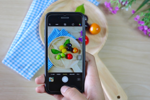 Foto seção média de pessoa fotografando com frutas com telefone inteligente