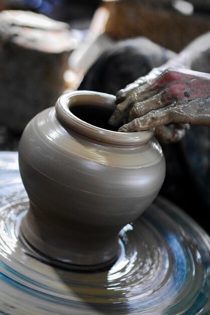 Seção média de pessoa moldando cerâmica em roda de cerâmica