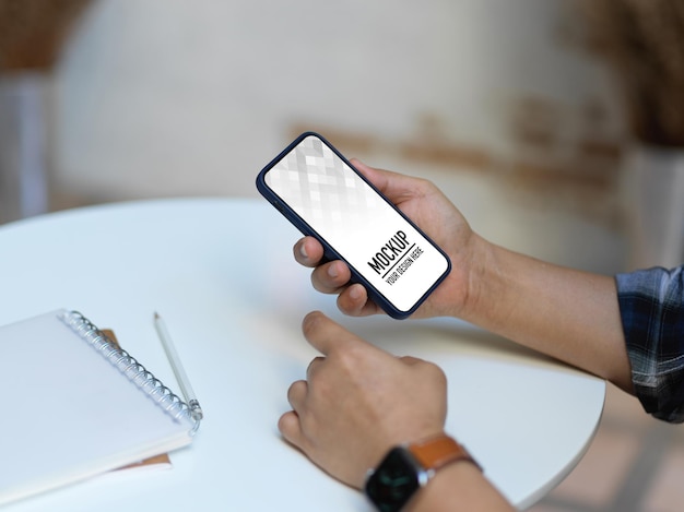 Seção média de pessoa usando telefone móvel na mesa