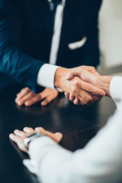 Seção média de pessoas de negócios dando um aperto de mão na mesa no escritório