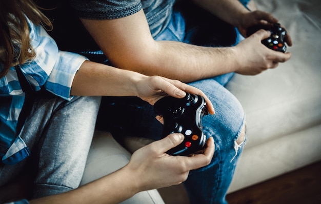 Seção média de pessoas segurando um controlador de videogame em casa