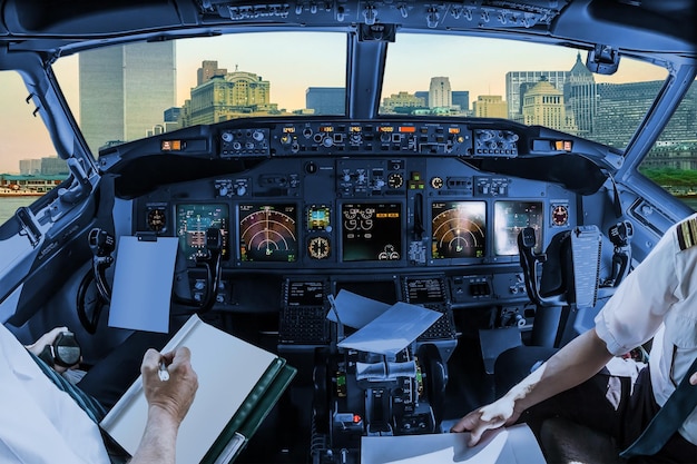 Seção média de pilotos segurando papel na cabine sobre a paisagem da cidade