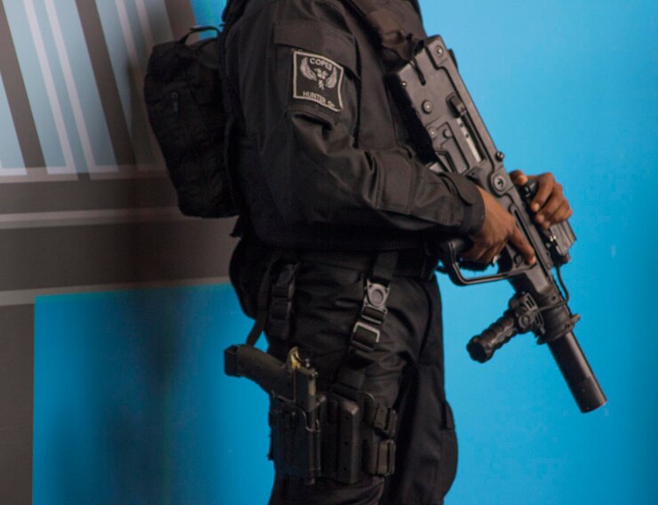 Foto seção média de soldado com arma contra a parede azul