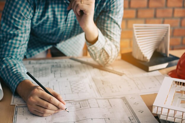 Foto seção média de um arquiteto trabalhando em um plano em uma mesa no escritório