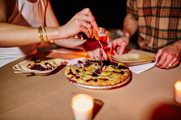 Foto seção média de um casal a comer tartes na mesa.