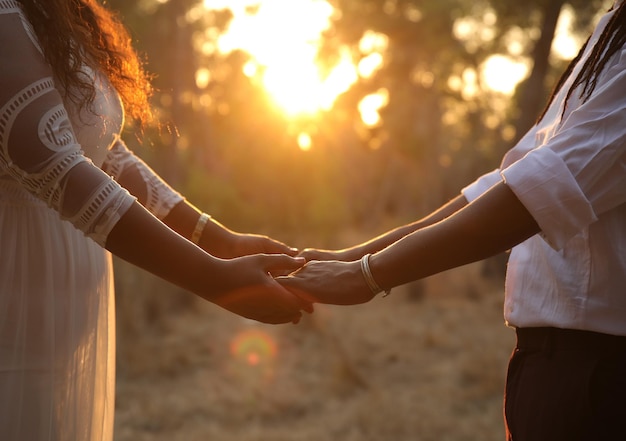 Foto seção média de um casal de mãos dadas enquanto está de pé no parque durante o pôr do sol