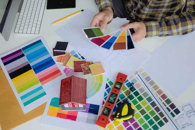 Seção média de um empresário segurando amostras de cores sobre a mesa no escritório