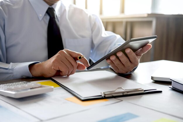 Seção média de um empresário usando um tablet digital na mesa no escritório
