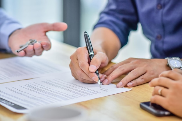 Seção média de um homem a assinar um contrato na mesa.