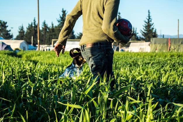 Foto seção média de um homem carregando a bola com um cão no campo