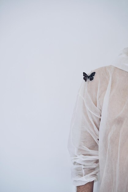 Foto seção média de um homem com borboleta artificial no ombro contra fundo branco