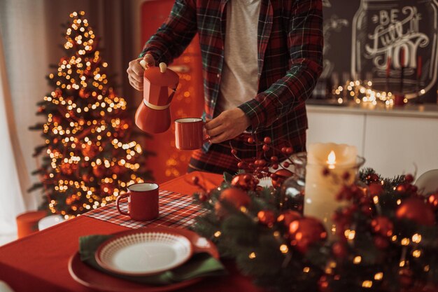 Seção média de um homem de pé junto à árvore de Natal na mesa