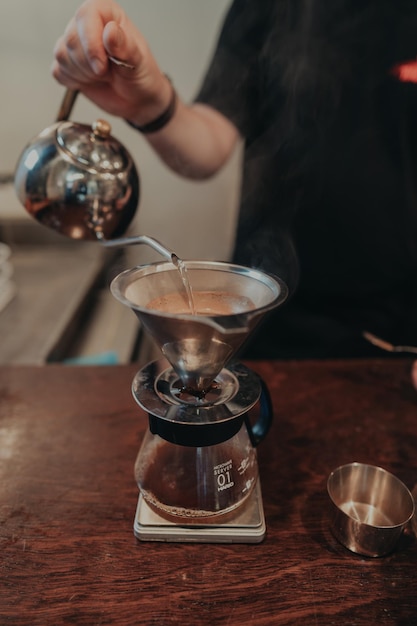 Seção média de um homem derramando café em uma xícara na mesa