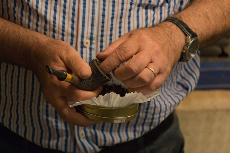 Foto seção média de um homem enchendo tabaco em um cachimbo de fumo