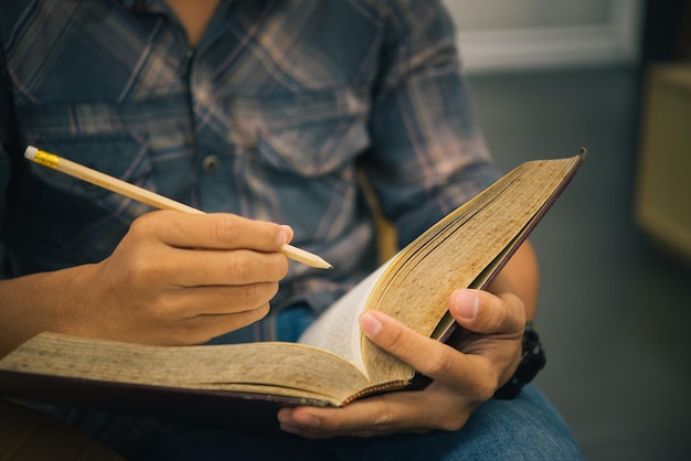 Seção média de um homem escrevendo em um livro