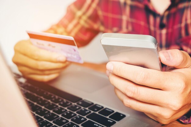 Foto seção média de um homem fazendo compras on-line usando o telefone na mesa