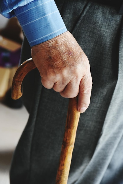 Seção média de um homem idoso segurando uma bengala de caminhada