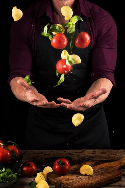 Foto seção média de um homem jogando vegetais de pé contra um fundo preto