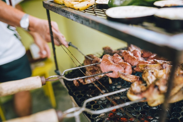 Seção média de um homem preparando carne em uma grelha de churrasco