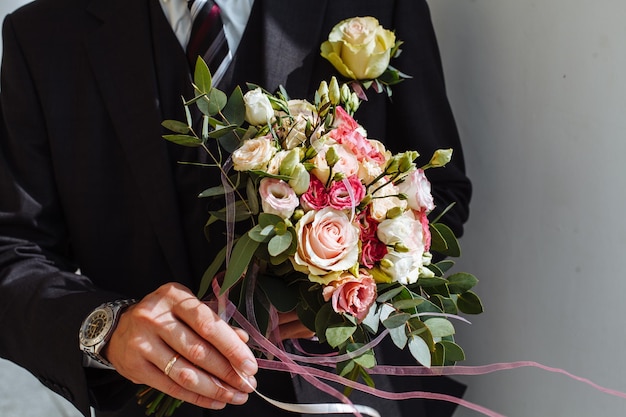 Seção média de um homem segurando um buquê de rosas