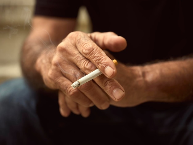 Foto seção média de um homem segurando um cigarro