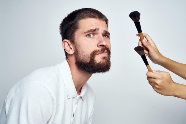 Seção média de um homem segurando um pincel de maquiagem contra um fundo branco