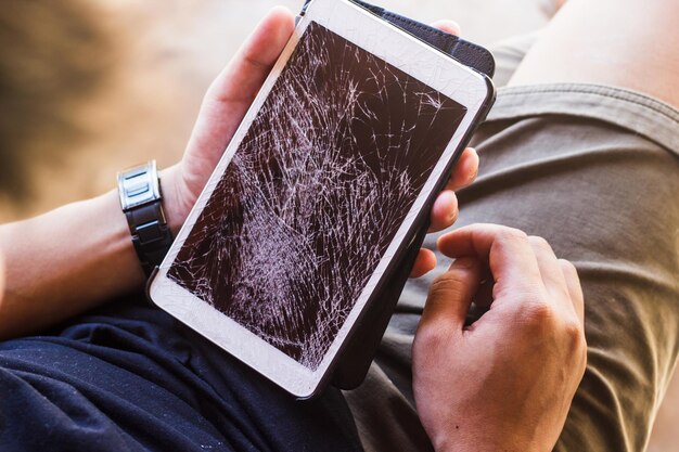 Foto seção média de um homem segurando um tablet digital danificado
