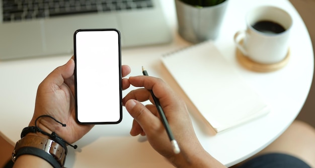 Seção média de um homem segurando um telefone celular na mesa