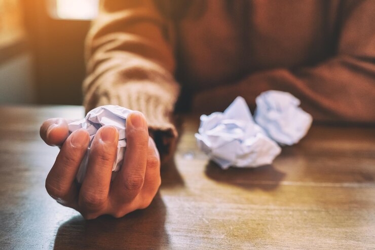 Foto seção média de um homem segurando uma bola de papel arrugada na mesa