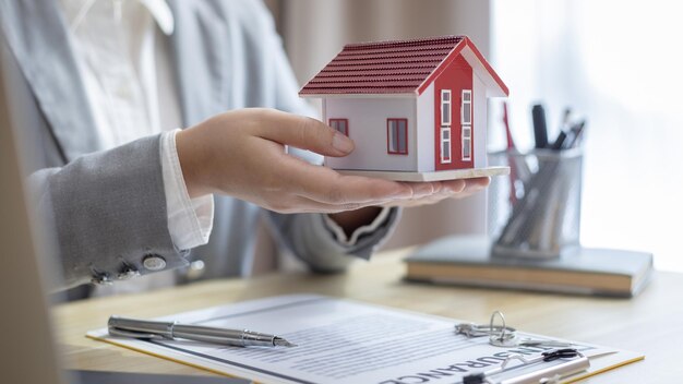 Seção média de um homem segurando uma casa modelo na mesa