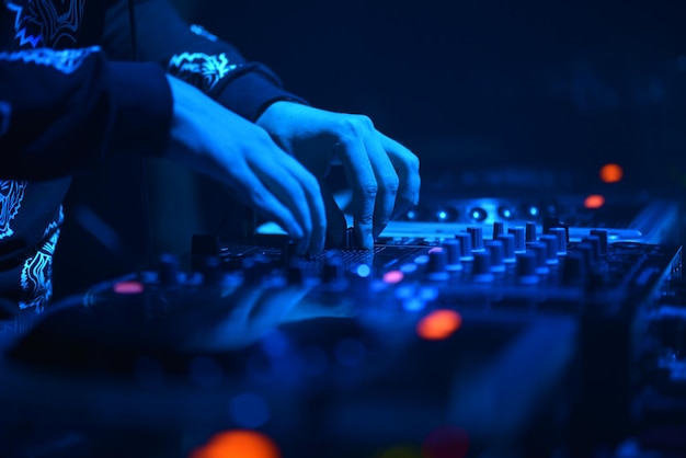 Seção média de um homem tocando um mixador de som em um clube