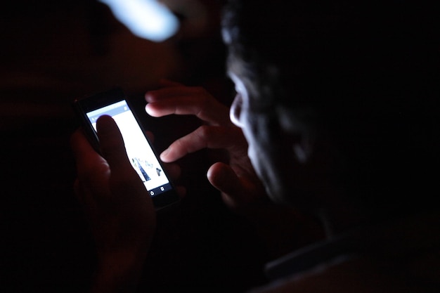 Foto seção média de um homem usando telefone celular em casa