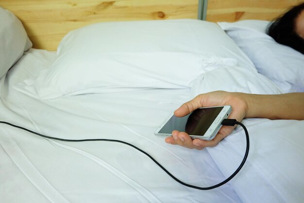 Seção média de um homem usando telefone celular na cama