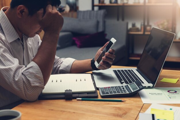 Seção média de um homem usando telefone móvel enquanto está sentado na mesa