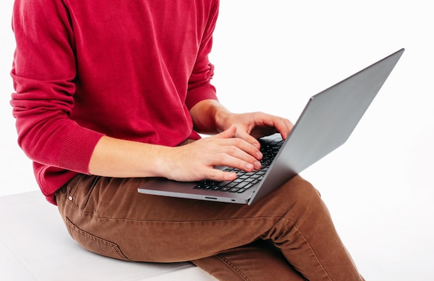 Seção média de um homem usando um laptop enquanto está sentado sobre um fundo branco