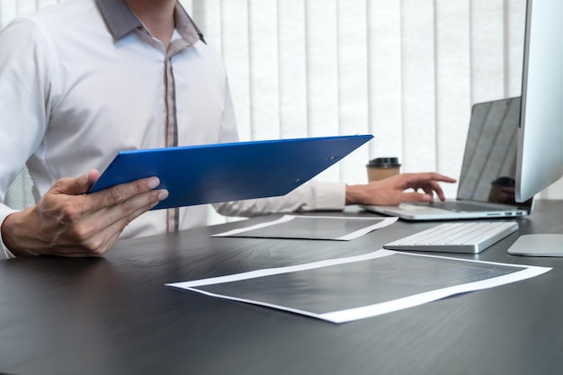 Seção média de um homem usando um laptop no escritório
