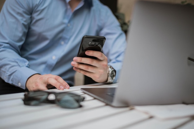 Foto seção média de um homem usando um telefone móvel enquanto está sentado com um laptop na mesa