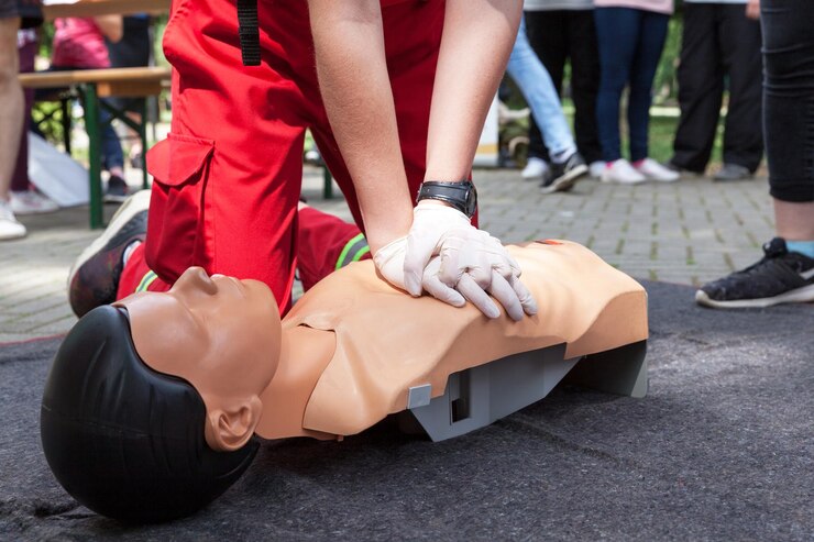 Foto seção média de um instrutor ensinando paramédico enquanto realiza cpr em um manequim em uma calçada na cidade