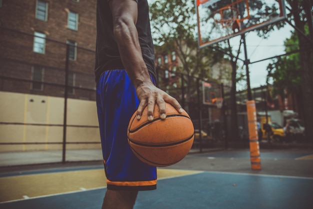 Foto seção média de um jovem segurando uma bola de basquete na quadra