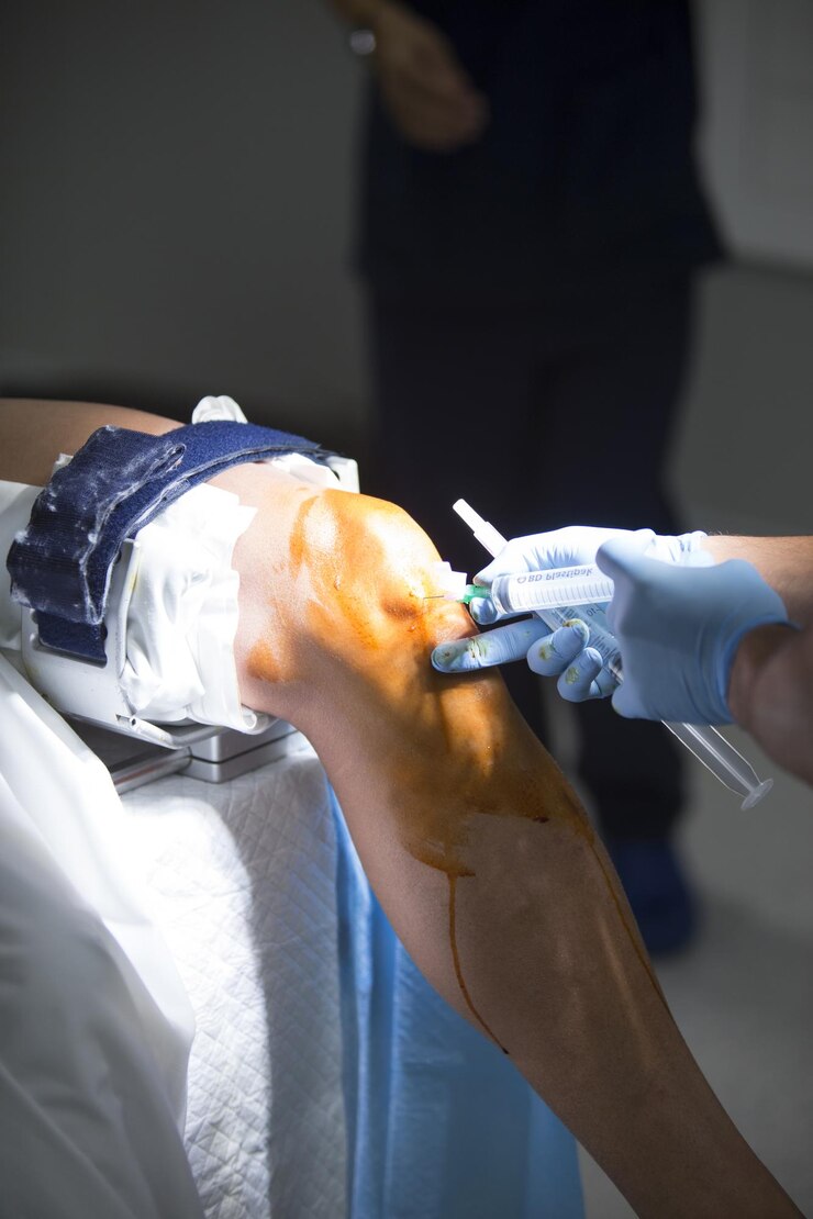 Foto seção média de um médico injetando uma seringa na perna do paciente na sala de cirurgia