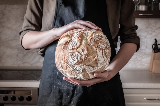 Seção média de um padeiro segurando pão assado em uma padaria