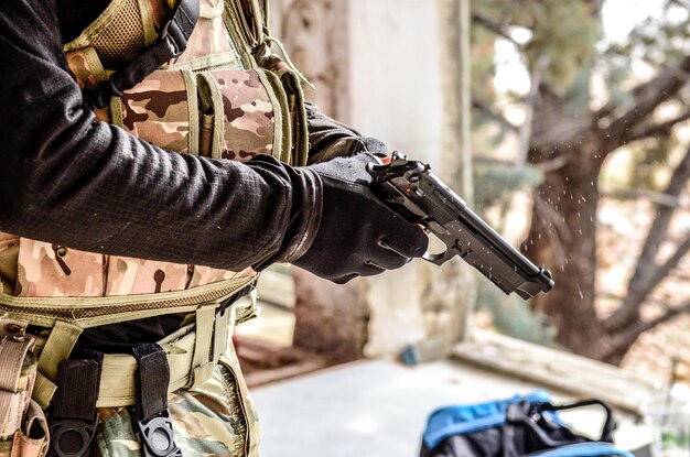 Foto seção média de um soldado do exército apontando uma pistola contra árvores