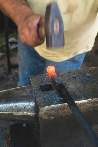 Foto seção média de um trabalhador manual batendo em metal fundido na indústria